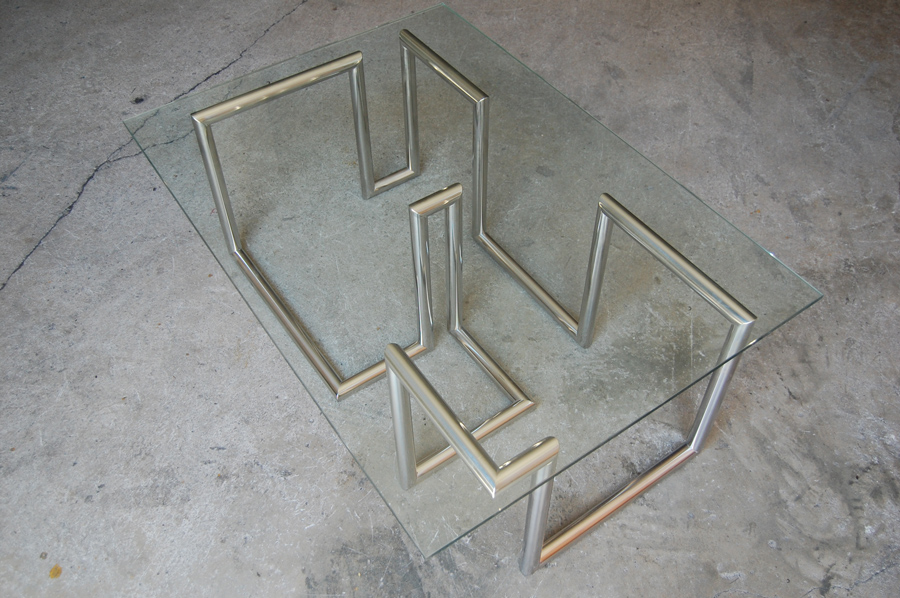 HUGO CHALÉ - Artista y escultor conceptual - Mobiliario Mesa Waves  realizada en acero inoxidable y cristal ahumado